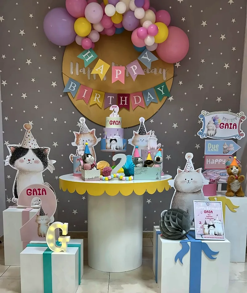 Il tavolo della torta allestito a tema gattini, con l'arco di palloncini