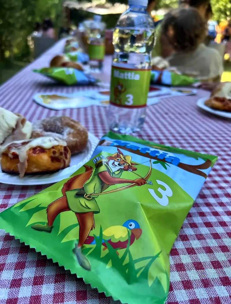 La tavola in giardino con bottiglietta e sacchetto personalizzati col nome del festeggiato