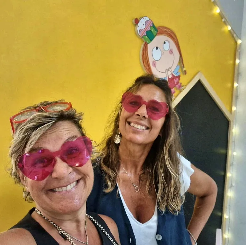 Giada e Simona sorridenti, con gli occhiali a forma di cuore, nel locale di Maffy Junior