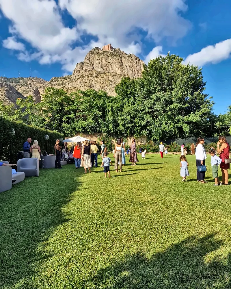 Genitori e bambini a una festa sul prato, sotto il Castello Utveggio