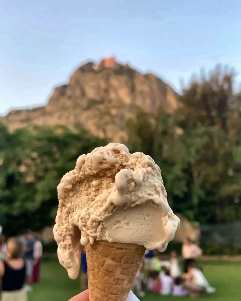 Un cono gelato in primo piano, con il castello e la festa sullo sfondo