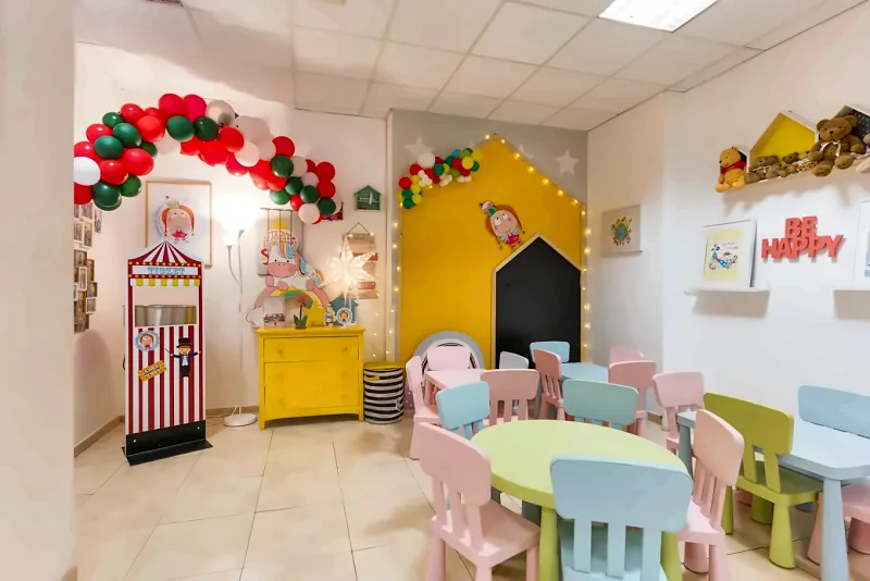 La sala delle feste di Maffy Junior: tavolini e sedie colorate, il teatrino e la casetta gialla