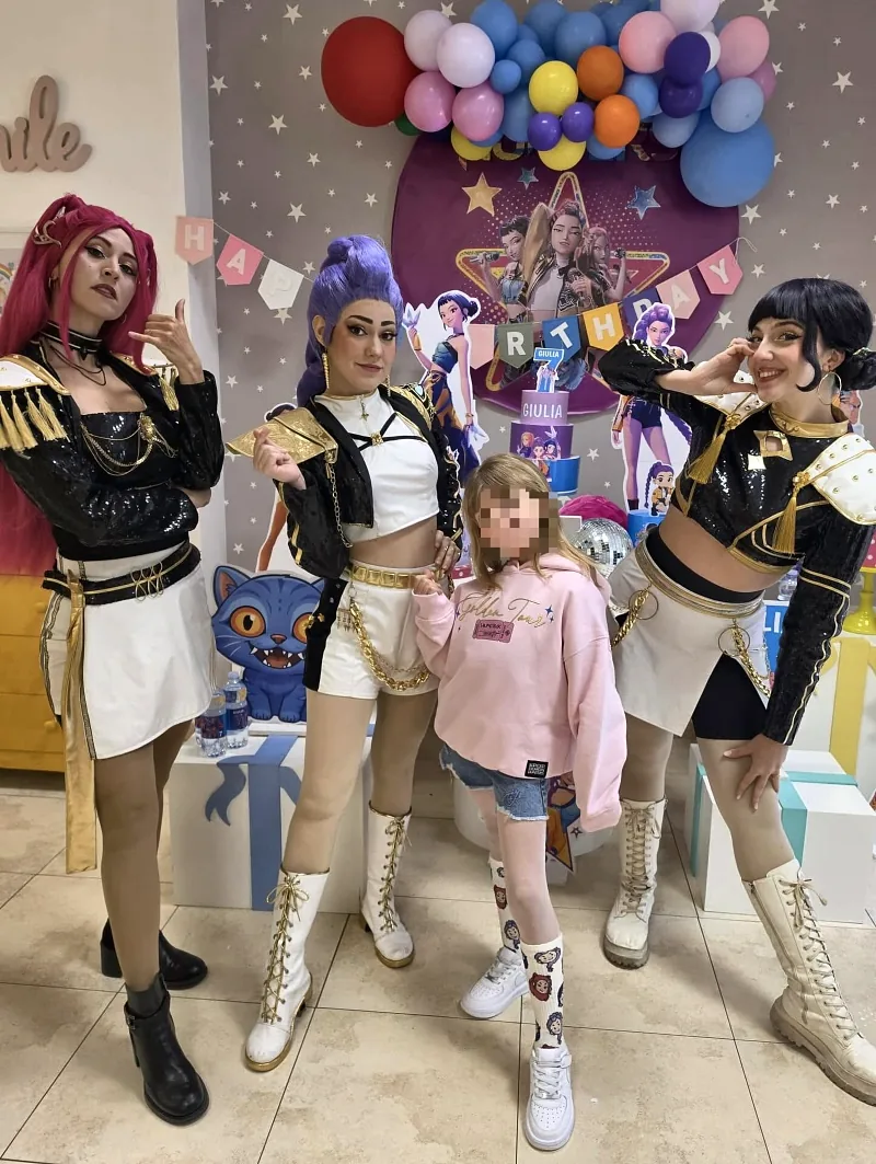 Tre animatrici vestite da cantanti pop con la festeggiata, davanti all'allestimento a tema